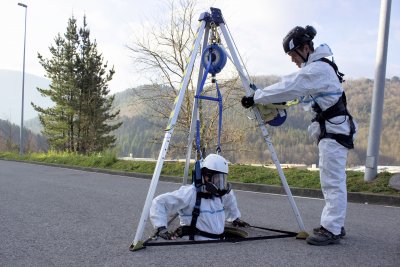 Man som firas ner i brunn med tripod för nedfirning