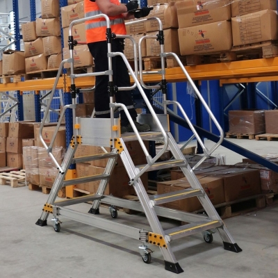 Miljöbild där en man med svarta arbetskläder och reflexväst står på en dubbelsidad arbetsplattform