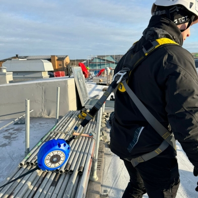 Baksida på svart och gul fallskyddssele på man på frostigt tak