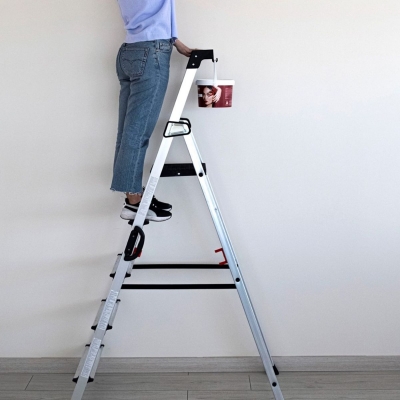 Miljöbild där en kvinna står på en trappstege och målar i taket