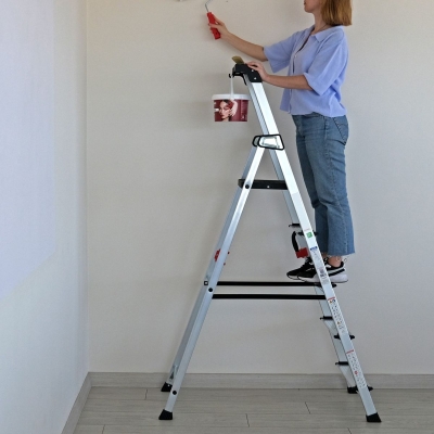 Miljöbild där en kvinna står på en trappstege och målar i taket