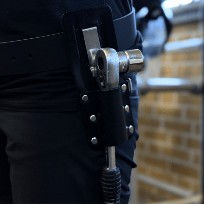 Hållare för vattenpass/spärrskaft med ProClip monterad i bälte, där spärrskaftet sitter säkert och lättåtkomligt under arbete.