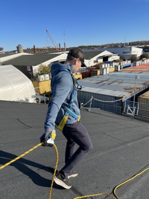 man gåendes på tak med fallskyddspaket med rep