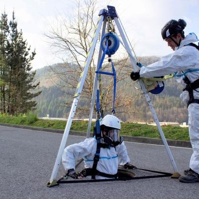 Blå nedfirningssling för tripod med man som firas ner i brun med tripod