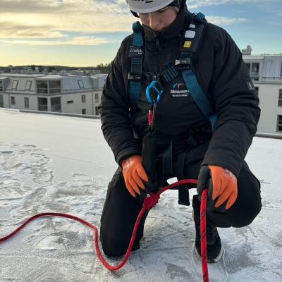 blå fallskyddsssele med midjeband och ryggplatta på frostigt tak framifrån