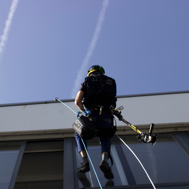 man hängandes vid husfasad i räddningskit